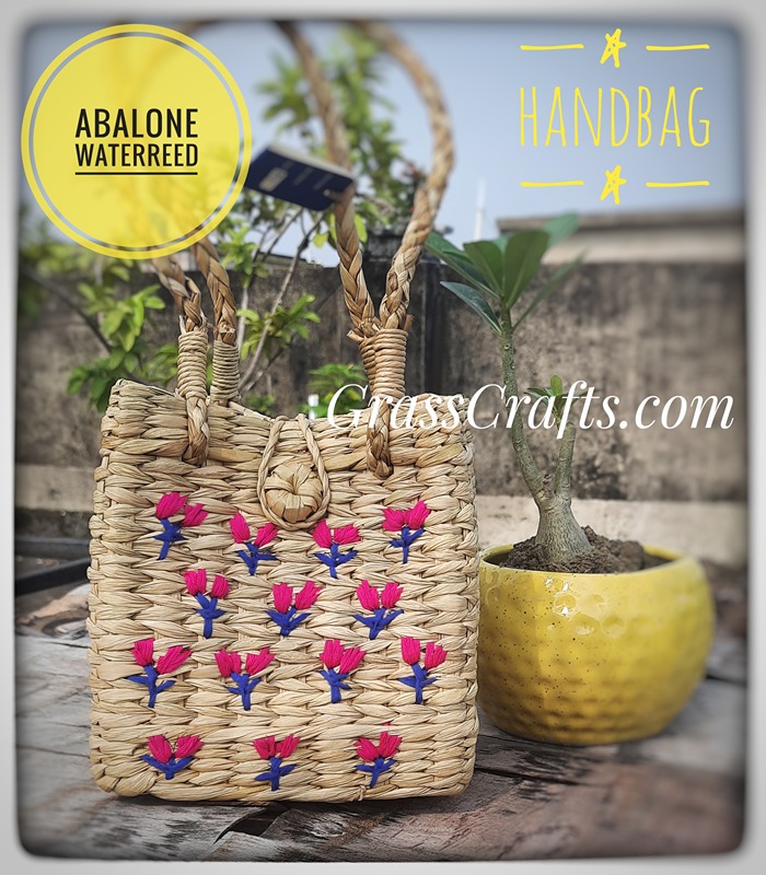a hand woven straw bag with flowers embroidered on it