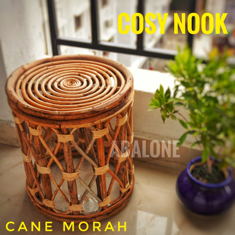 a round cane stool stool next to a potted plant on a balcony
