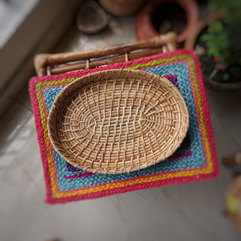 a hand woven cane round basket on a colorful mat