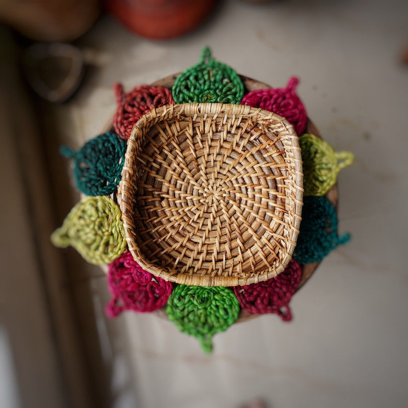 a hand woven cane square basket on a colorful mat