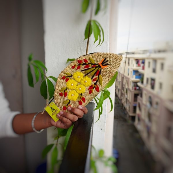 a hand embroidered organic straw clutch with colorful flowers