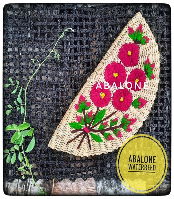 a hand embroidered organic straw clutch with colorful flowers