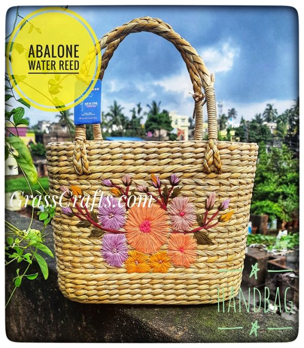a handmade straw bag with flowers embroidered on it