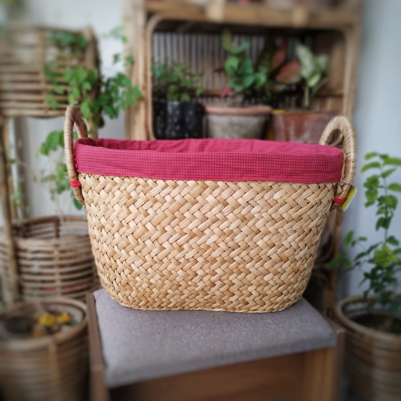 a laundry basket with a red cover and cane handle