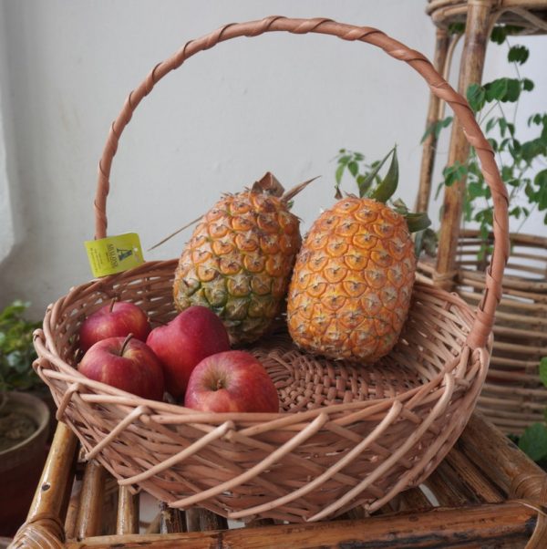 a fruit basket with a handle on a table